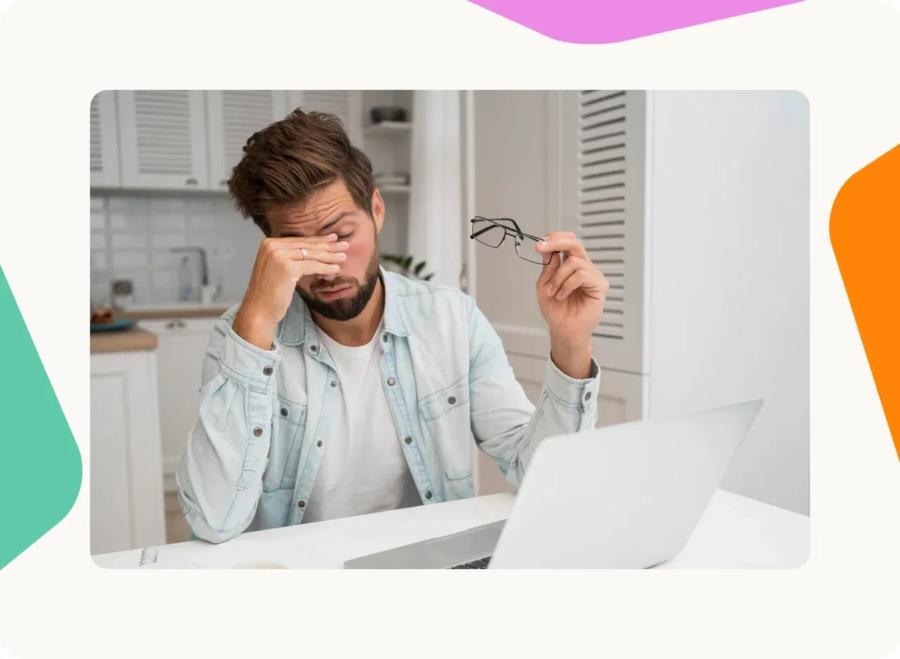 Employee rubbing tired eyes while working at a laptop