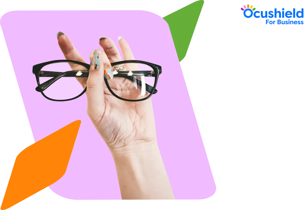 Hand holding a pair of glasses against a pink backdrop
